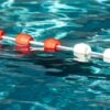 Schwimmleine mit roten und weißen Bojen im klaren Poolwasser.