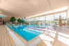 Hallenbad mit großem Schwimmbecken und Fensterfront.
