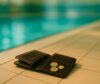 Offene Geldbörse mit Münzen auf dem Beckenrand eines Schwimmbads.
