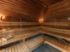 Innenaufnahme einer Sauna mit Holzbänken und warmem Licht.