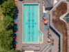 Luftaufnahme eines Außenschwimmbeckens mit abgetrennten Bahnen und blau-roten Liegestühlen