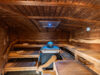 Sauna mit Holzbänken, rustikalen Wandverzierungen und einem Saunaofen in der Mitte, dazu ein Sternenhimmel-Effekt an der Decke.